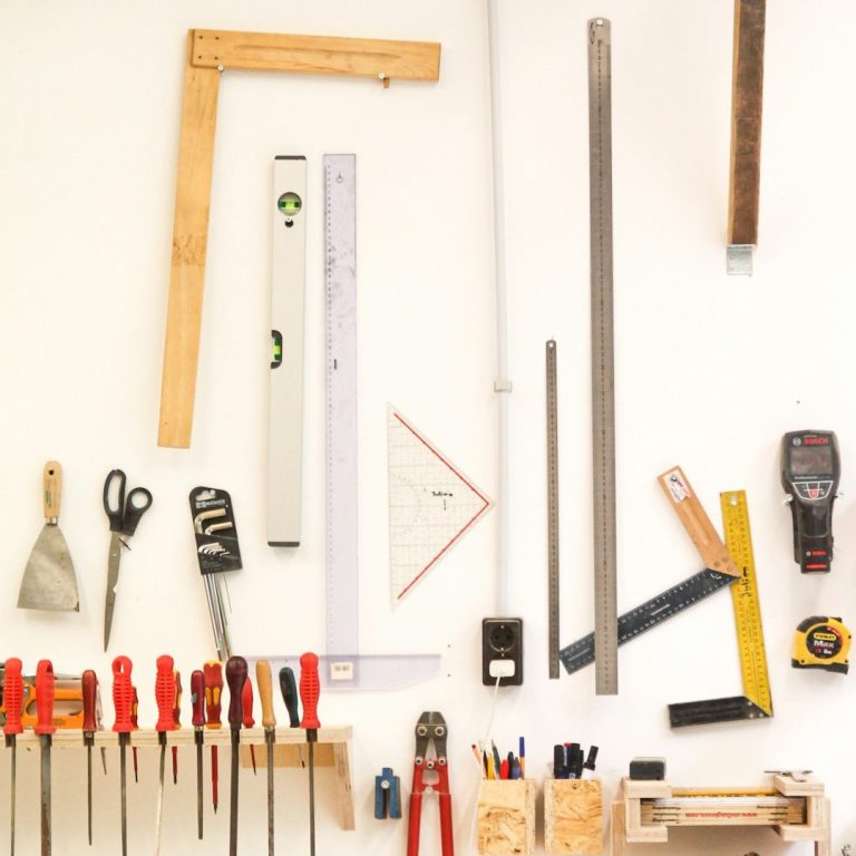 A collection of woodworking tools and measurement instruments arranged on a wall.