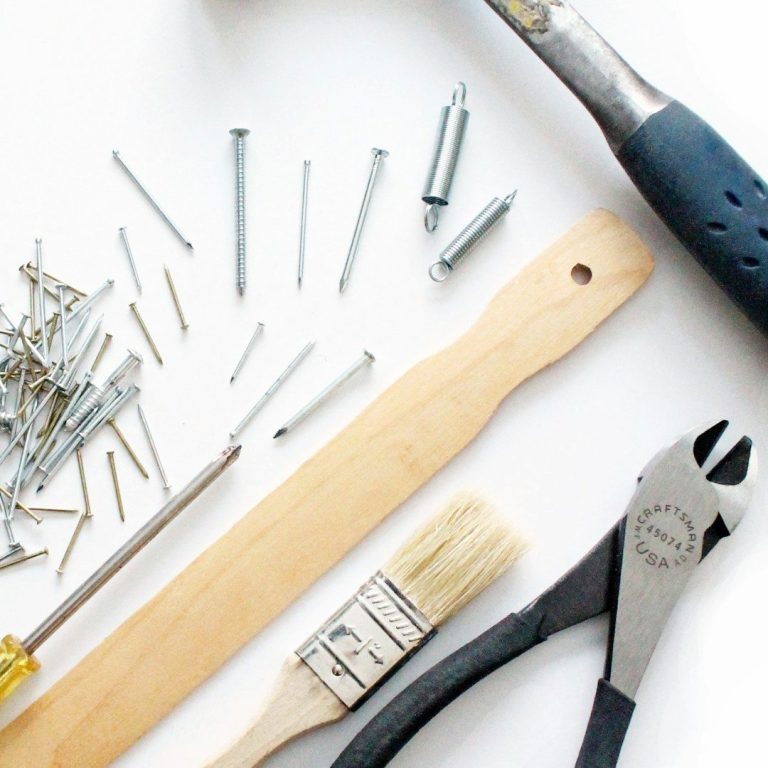 Assorted hand tools including screws, a hammer, pliers, a screwdriver, and a brush.